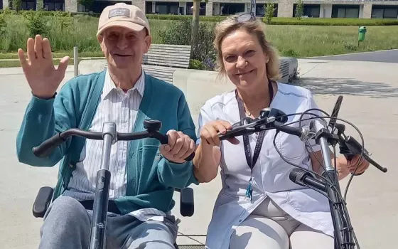 De kinesitherapeut met een bewoner op de duofiets